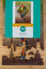 Lade das Bild in den Galerie-Viewer, Holzpuzzle &quot;Selfie im Geschenkeladen&quot; von BirkenPuzzle. Wanddekor aus Holz. Hausdekor, Tischspiel und Spielzeug, Schwarzwaldmalerei und Schwarzwald Geschenk. Puzzleteile:  Freiburg Münster, Schwabentor, historisches Kaufhaus, Martinstor, Schauinsland, Kuckucksuhren, Bächleboot, Schwarzwälder Kirschtorte, Schwarzwälderin, Bollenhut, Tracht, Hirsch, Birkhuhn, Adler, Hase, Berge, Fahrradfahrer, Tanne. Verpackung. 
